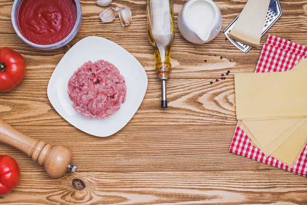 Mince, pasta, cheese, tomatoes and other on wooden table, top view. - Foto, afbeelding