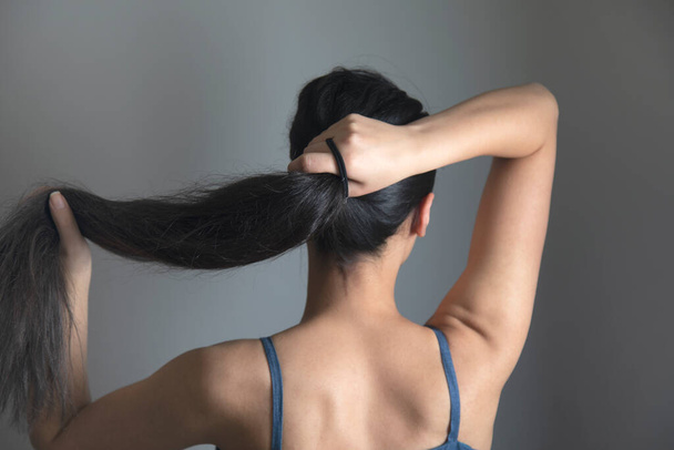 woman tail tie the hair on grey background - Foto, afbeelding