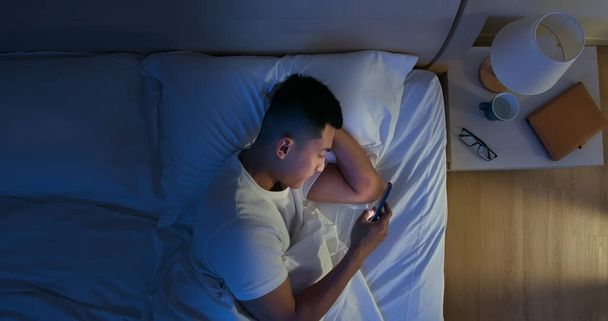 Overhead View of asian man use smartphone on bed at night - Fotografie, Obrázek