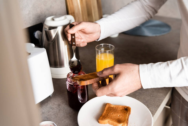 partial view of man spreading jam on toast for breakfast - Valokuva, kuva