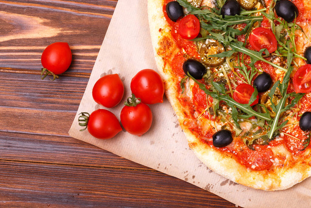 klassieke Italiaanse pepperoni pizza pinza met olijven en arugula. bovenaanzicht - Foto, afbeelding