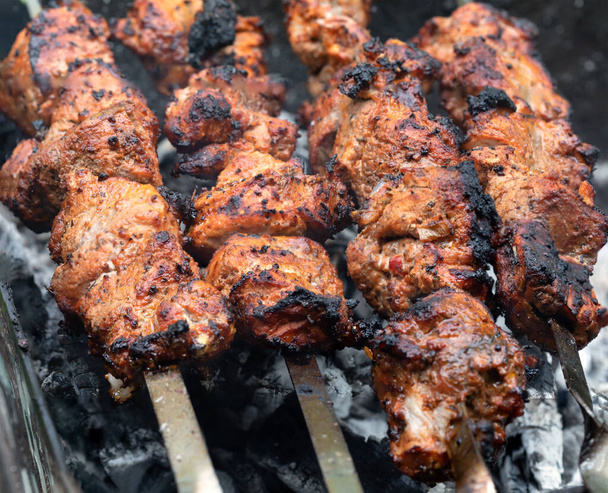 Meat on skewers. Marinated shashlik preparing on a barbecue grill over charcoal. Appetizing meat grilled on skewers. Cooking shashlik. Grilling pork on coal - Foto, Imagem