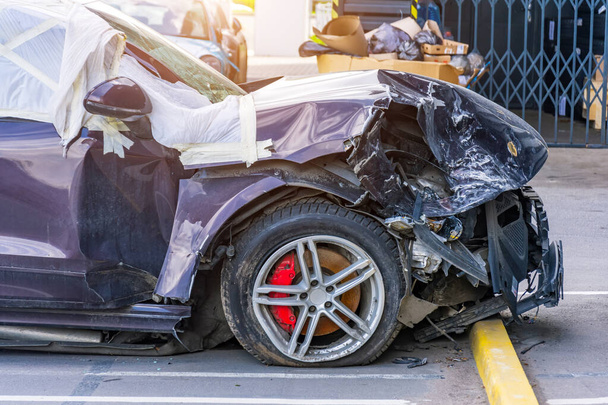 Σπασμένο κινητήρα εμπρός κουκούλα και τροχούς προφυλακτήρα ενός επιβατικού αυτοκινήτου σε ένα χώρο στάθμευσης - Φωτογραφία, εικόνα