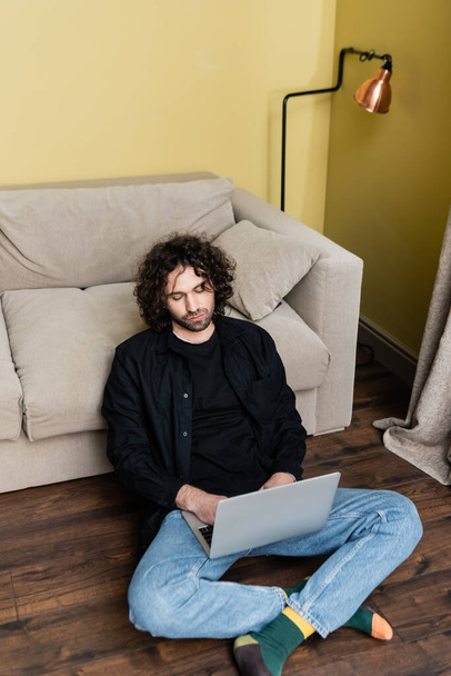 Handsome man using laptop on floor in living room - Photo, Image