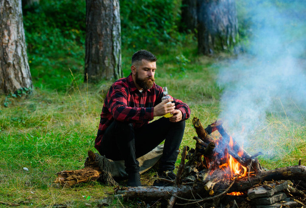 Handsome macho with beer sitting near bonfire, - Zdjęcie, obraz