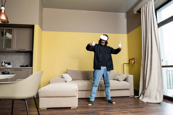 Homme montrant comme geste tout en utilisant casque de réalité virtuelle dans le salon
 - Photo, image
