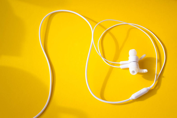 White wired headphones on a yellow background. Colorful spring concept. - Foto, Bild