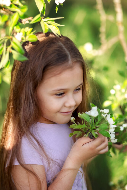 little girl with long hair near a flowering tree - Zdjęcie, obraz