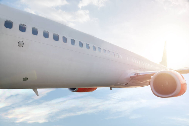 Samolot z boku samolotu komercyjnego lecący na czystym niebie nad chmurami i słońcem za nim piękne światło globalne podróże i podróże przygodowe Sunlight and flare background concept. - Zdjęcie, obraz