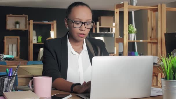 Jovem afro-americana trabalhando no laptop moderno no escritório
 - Filmagem, Vídeo