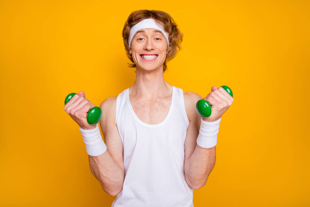 Close-up portrait of his he nice attractive funky glad cheerful cheery guy doing work out with small light dumbbell leisure isolated over bright vivid shine vibrant yellow color background - Photo, image