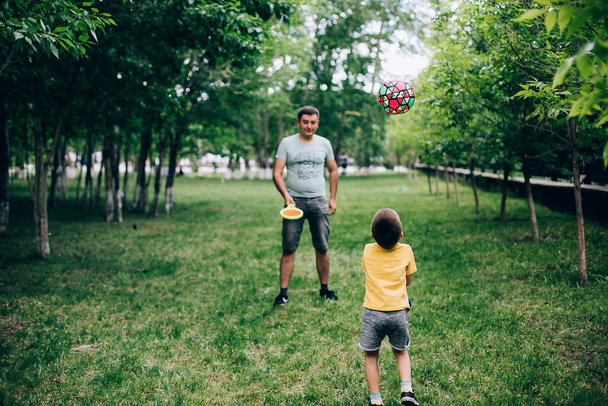 公園では若い白人の父と息子がボールと一緒に遊んでいた。夏休み週末子供レジャーコンセプト - 写真・画像