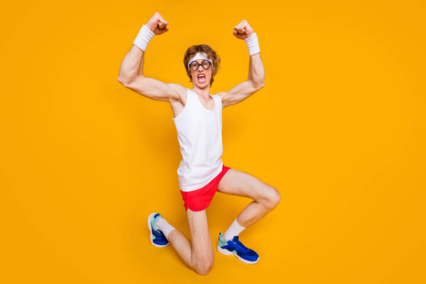 Full length body size view of nice funky successful cheerful cheery crazy motivated guy standing on knee showing muscles isolated over bright vivid shine vibrant yellow color background - Foto, Bild