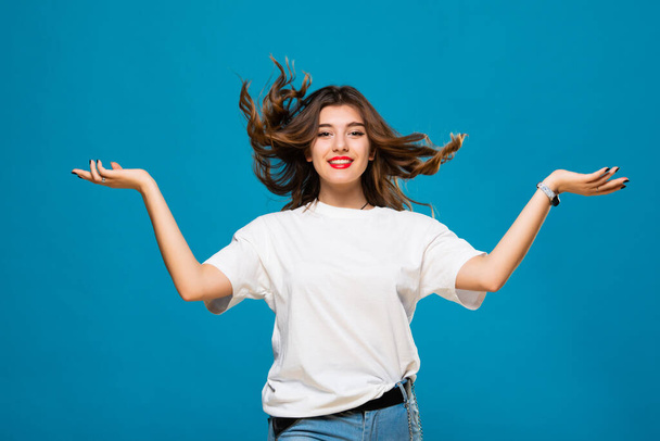 Cute girl student teenager with flying hair and a smile on his face on a blue background. The concept of happiness, carefree and positive. - 写真・画像