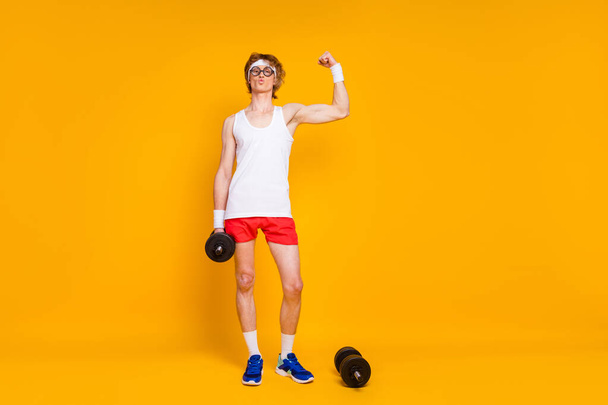 Full length body size view of nice attractive proud content slim thin fit foxy ginger guy sportsman doing work out showing result bicep isolated over bright vivid shine vibrant yellow color background - 写真・画像