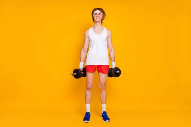 Full length body size view of his he nice attractive cheerful cheery slim thin guy sportsman doing work out holding in hand barbell isolated over bright vivid shine vibrant yellow color background - Photo, image