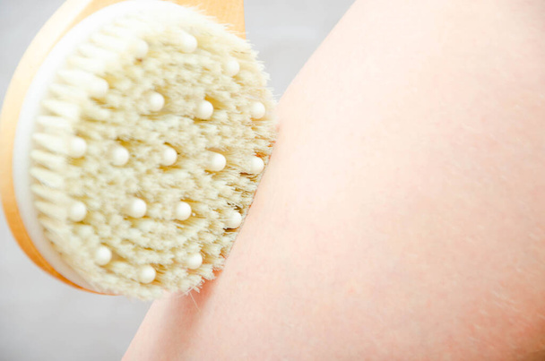 Trockenmassage. Massage zu Hause, im Salon mit einer Bürste aus natürlichen Borsten. Mädchen massiert Beine, Gesäß in Nahaufnahme - Foto, Bild
