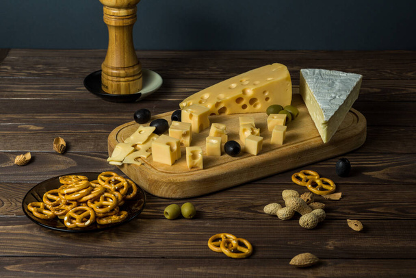 Tasting a cheese dish with herbs, snacks and salt on an old black wooden table. Food for wine and romance, cheese delicacies. Menu design horizontal. View from above. - Photo, Image