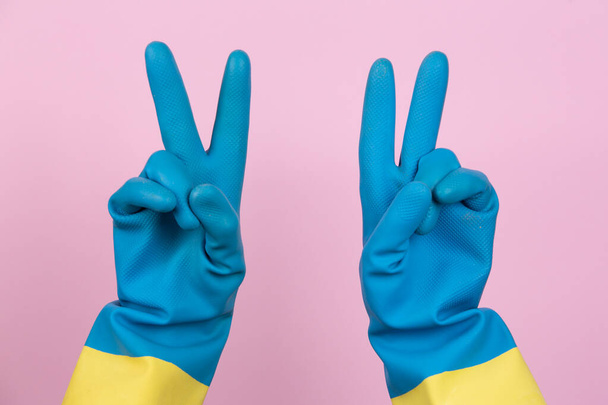 A cleaning gloved hand making the victory gesture - 写真・画像