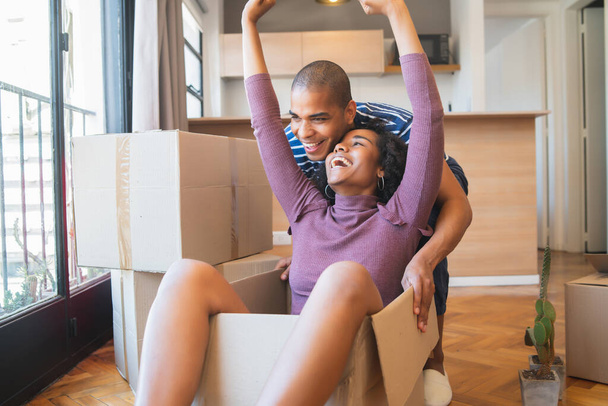Portrait of happy latin couple having fun with cardboard boxes in new house at moving day. Real estate concept. - Foto, immagini