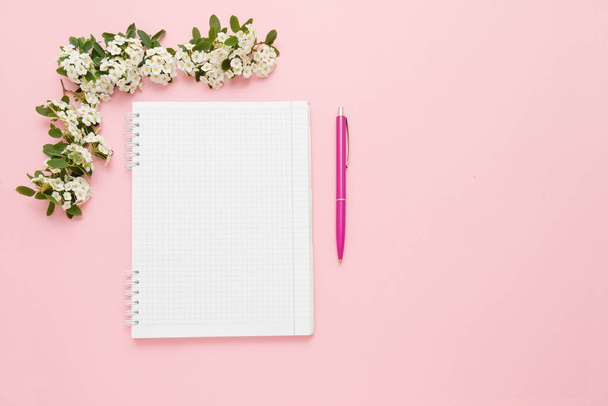 Top view notebook, pen and white flowers on a pink background. - Photo, image
