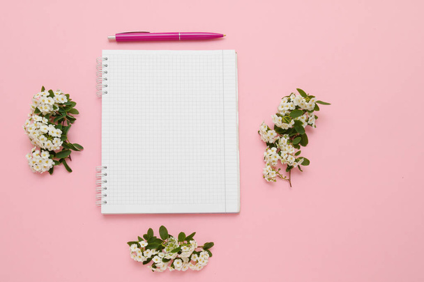 Top view notebook, pen and white flowers on a pink background. - Foto, Imagen