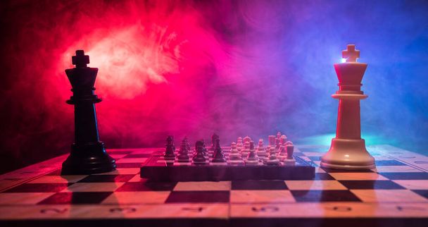 Hra na šachovnici s obchodními nápady a konkurencí. Šachové postavy na tmavém pozadí s kouřem a mlhou. Selektivní zaměření - Fotografie, Obrázek