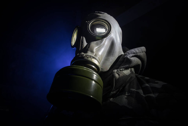 Environmental disaster. Post-apocalyptic survivor in gas mask on a dark background. Dramatic portrait of a man wearing a gas mask. Means for radiation protection. Selective focus - Photo, Image