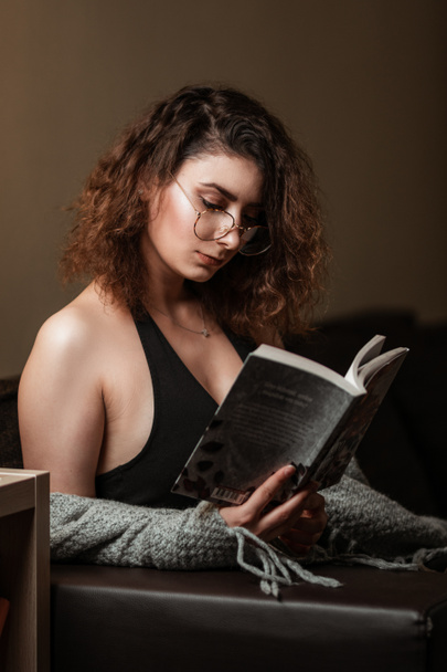 Image of a beautiful girl reading inside on a couch. - Foto, immagini