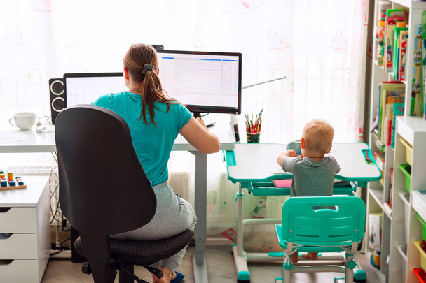 Mother with kid trying to work from home during quarantine. Stay at home, work from home concept during coronavirus pandemic - Foto, immagini