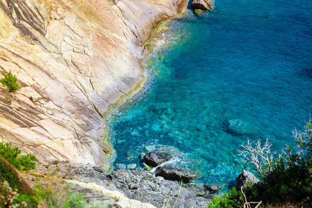 Costa costera con acantilado y rocas en una ladera de montaña. Mar azul de la isla de Elba en Italia en la región de Toscana. Mar cristalino. Mar Mediterráneo - Foto, imagen