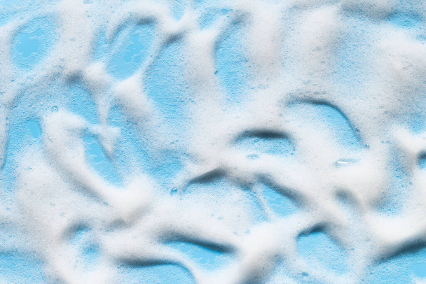 Αφρός σαπουνιού σε μπλε επιφάνεια. Σαμπουάν, καθαριστικό, αφρόλουτρο. Υγιεινό περιβάλλον μπάνιου. Αφηρημένες πιτσιλιές αφρού καθαρισμού - Φωτογραφία, εικόνα