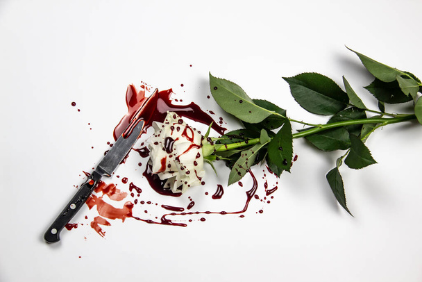 Schöne und blutige weiße Rose mit Messer auf weißem Hintergrund. Blutige Rose - Konzeptfoto. Weiße Rose mit Messer und Blut. - Foto, Bild