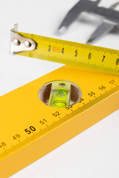 Yellow tape measure and spirit level on clear white background. Place for text. - Photo, Image