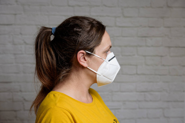 Jonge vrouw met KN-95 beschermend medisch masker. Preventie van de verspreiding van virus en epidemie, beschermend mondfiltermasker. Ziekten, griep, luchtverontreiniging, coronavirusconcept - Foto, afbeelding