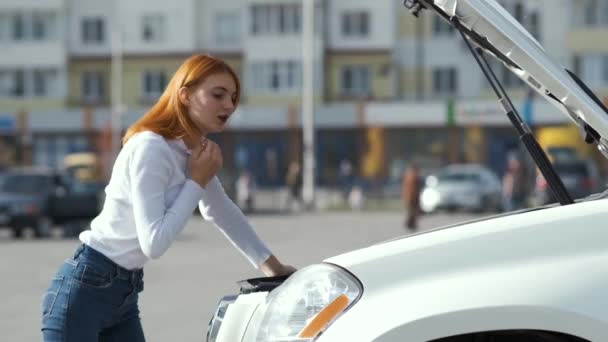 Young stressed woman driver near broken car with popped hood having a prbreakdown problem with her vehicle waiting for assistance. - Filmati, video