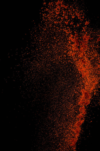 Red paprika spices powder explosion, flying chili pepper isolated on black background. Splash of spice background.  - Fotó, kép