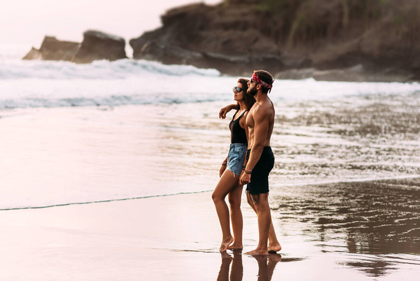 Piękna para na plaży spotyka zachód słońca. Zakochana para na piaszczystej plaży na wyspie Bali w Indonezji. Para na plaży. Kochankowie o zachodzie słońca. Podróż poślubna. Przestrzeń kopiowania - Zdjęcie, obraz