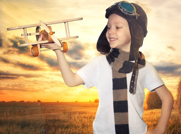 Child pilot aviator with airplane dreams of traveling in summer in nature at sunset - Foto, Bild