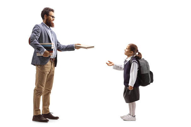 Full length profile shot of a male teacher giving a book to a female pupil isolated on white background - Φωτογραφία, εικόνα