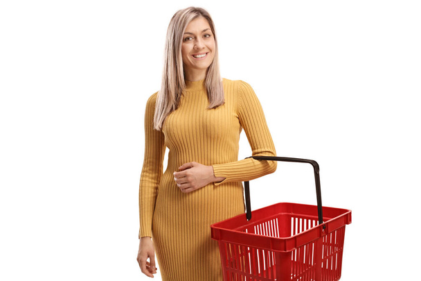 Young woman smiling and holding an empty shopping basket isolated on white background - 写真・画像