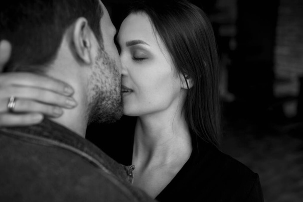 black and white photo, a woman kisses her man, a gentle hug, a wife kisses her husband, a touch of lips - Fotó, kép