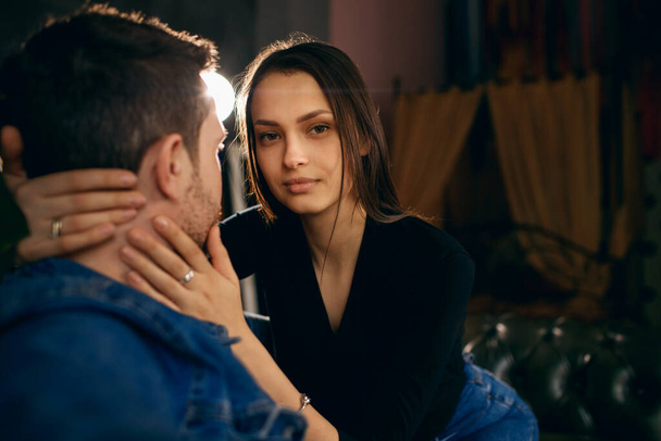 girl hugs her boyfriend or husband sitting on the couch, home interior, family relationships, young family, husband and wife spend time at home in quarantine, beautiful eyes, gentle hugs - Valokuva, kuva
