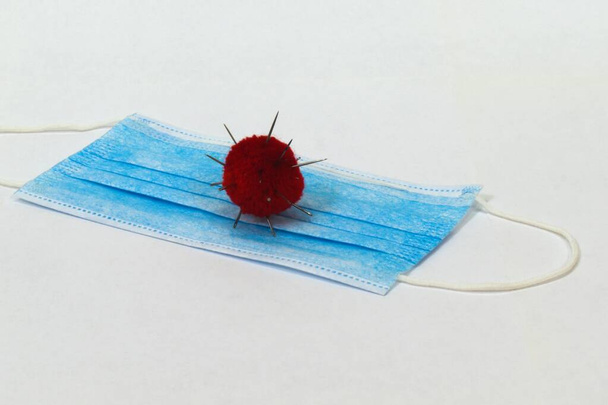 coronavirus model op antivirus masker rode bug op blauwe stof - Foto, afbeelding