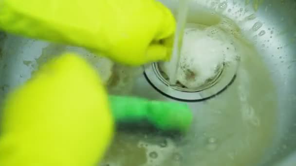 Ręka w gumowej rękawiczce myje wapno i rdzę z powierzchni zlewu gąbką i zmywa ją strumieniem wody. - Materiał filmowy, wideo
