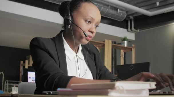 Down uitzicht op moe Afrikaans amerikaanse vrouw met headset klaar met praten met een klant - Video