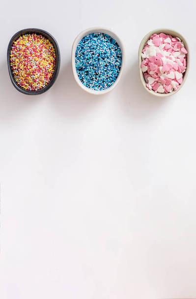 Des bols pleins de doux multicolores décoratifs. Décorations de sucre de cuisson, fond blanc. Espace de copie
. - Photo, image