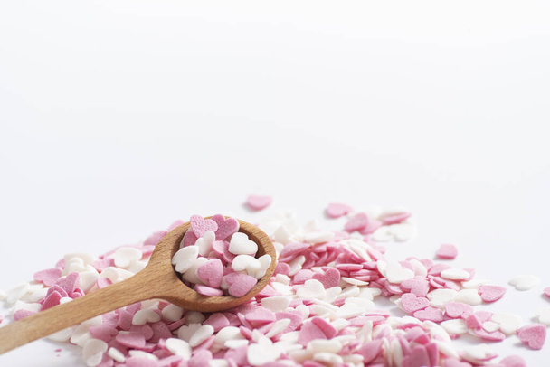 Łyżka pełna słodkich dekoracyjnych różowych i białych serc. Dekoracje do pieczenia, Sugar Heart w drewnianej łyżce pomiarowej, blisko - Zdjęcie, obraz