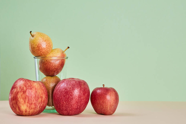 Ripe pears in glass. Red apples on table. Eco-friendly food. Summer fruits. Copy space. Pastel green background - Foto, Imagen