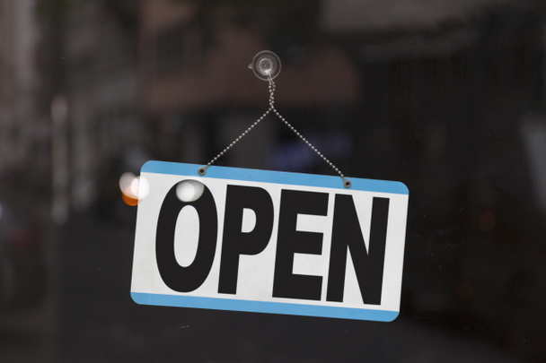 Close-up em um sinal azul aberto na janela de uma loja exibindo a mensagem "Abrir
" - Foto, Imagem